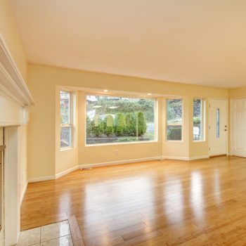 Empty living room interior with polished hardwood floor. Empty living room interior with polished hardwood floor, large window and entrance door. Northwest, USA
