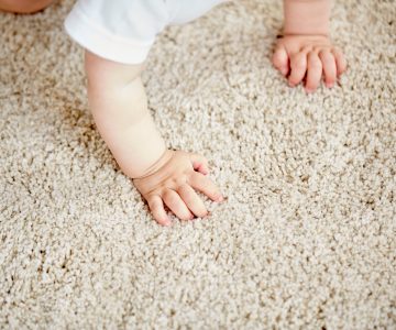 hands of baby crawling on floor or carpet childhood, babyhood and people concept - hands of baby crawling on floor or carpet
