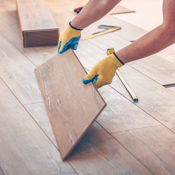 Professional installation of floor covering, the worker quickly and qualitatively mounts a laminate board Professional installation of floor covering, the worker quickly and qualitatively mounts a laminate board