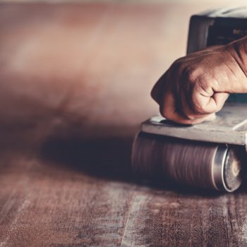 The carpenter uses power sander as a powerful tool in wood finishing. A skilled carpenter is using the power sander as a tool to polish his furniture instead of sandpaper.