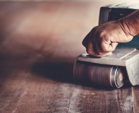 The carpenter uses power sander as a powerful tool in wood finishing. A skilled carpenter is using the power sander as a tool to polish his furniture instead of sandpaper.
