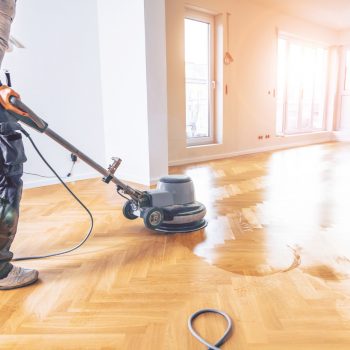 Varnishing of oak parquet floor, workers hand and tool Varnishing of oak parquet floor, workers hand and tool