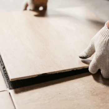 The hands of the tiler are laying the ceramic tile on the floor. Close up macro shot. Home renovation and building new house concept The hands of the tiler are laying the ceramic tile on the floor. Close up macro shot. Home renovation and building new house concept